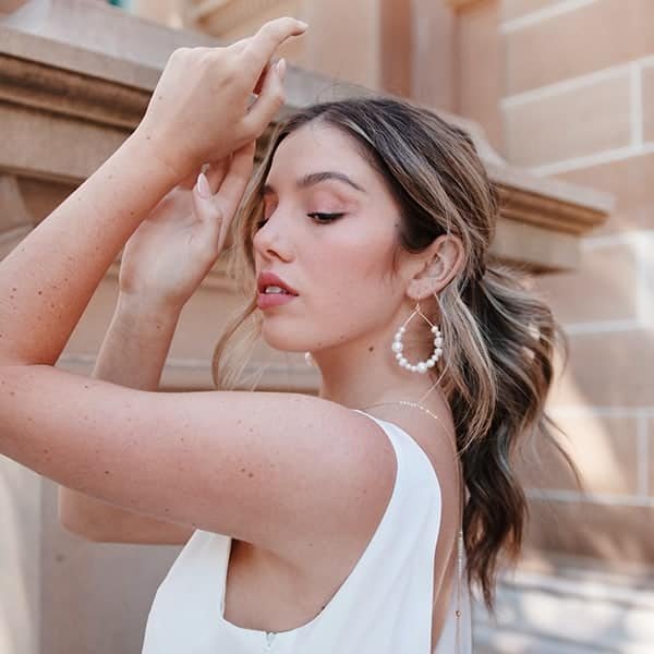 Décorative Fille avec les mains en l'air habiller avec une jupe blanche devant un mur en pierre