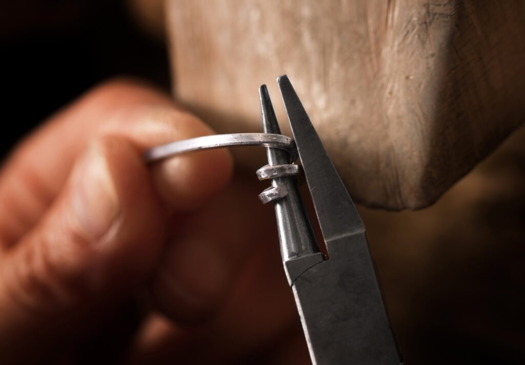 Pince qui modèle un fil d’aluminium manipuler par une main avec un fond bois