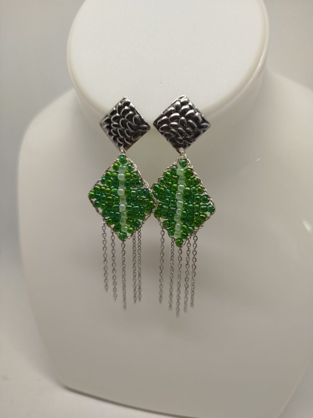 boucles d'oreilles créées en perles vertes en forme carré avec morceaux de chaîne pendantes. Les clous d'oreilles argentés sont carrés en acier hypoallergénique.