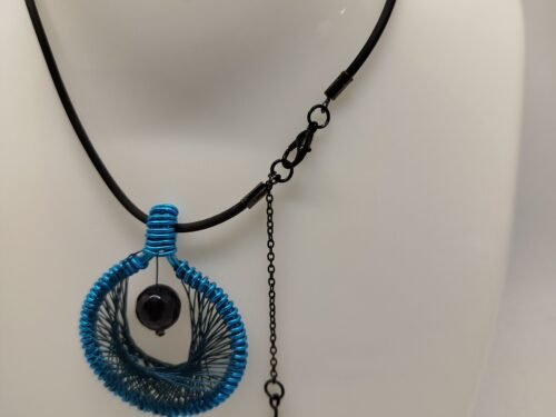 Le pendentif de 4 cm créé en fil aluminium turquoise et tissé à l'intérieur. Une belle pierre Onyx à facettes est fixé au centre.Le collier de 45 cm de longueur est en caoutchouc avec fermoir mousqueton.