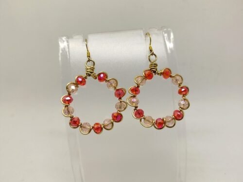 créoles 3 créoles façonnées avec des perles en verre à facettes rouge, entourées avec du fil aluminium doré. Leur diamètre est de 3 cm. Les crochets sont de couleur dorée et en acier chirurgical et hypoallergénique