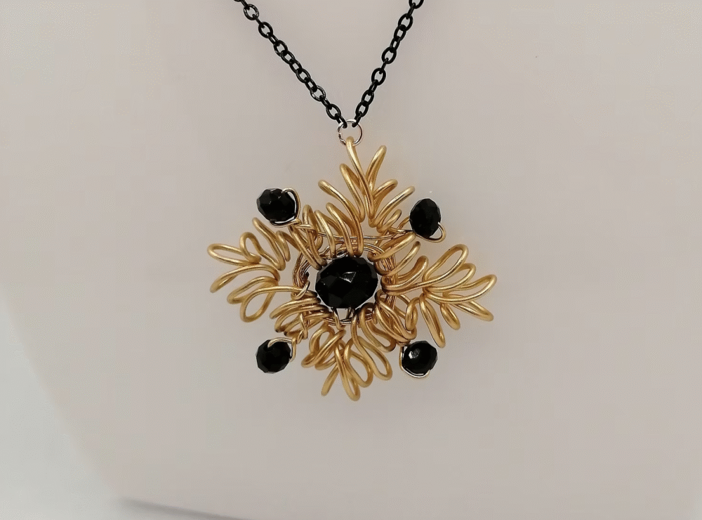 collier en forme de flocon avec fil aluminium doré et pierre onyx au centre