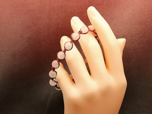 bracelet soigneusement confectionné à la main avec 13 magnifiques pierres naturelles quartz rose , entourées avec plusieurs fils aluminium rouge
