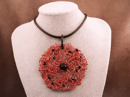 Le pendentif de 6,5 cm façonné à la main en fil d’aluminium rouge, et des perles à facettes noires, une pierre naturelle Onyx au centre