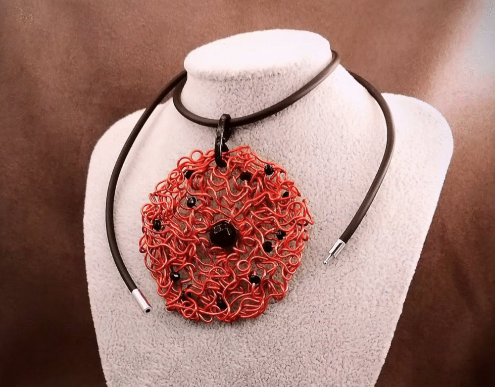 Le pendentif de 6,5 cm façonné à la main en fil d’aluminium rouge, et des perles à facettes noires, une pierre naturelle Onyx au centre fermoir aimanté
