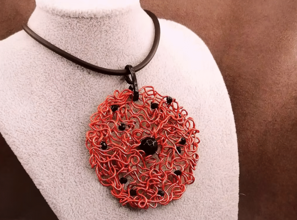 Le pendentif de 6,5 cm façonné à la main en fil d’aluminium rouge, et des perles à facettes noires, une pierre naturelle Onyx au centre