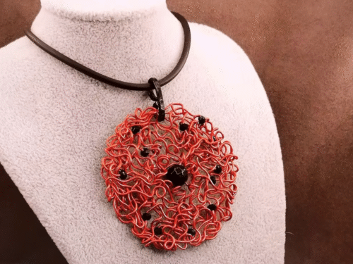 Le pendentif de 6,5 cm façonné à la main en fil d’aluminium rouge, et des perles à facettes noires, une pierre naturelle Onyx au centre