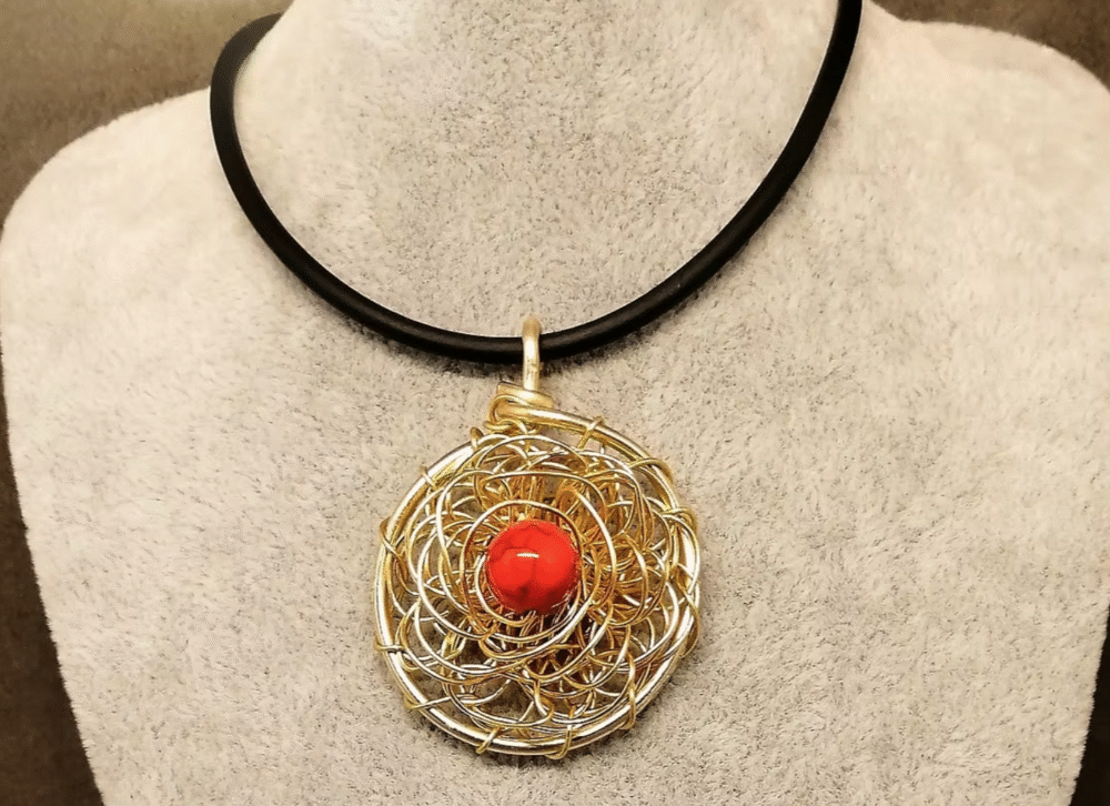 pendentif créé en fil aluminium doré en forme de fleur et pierre naturelle howlite rouge fixée au centre