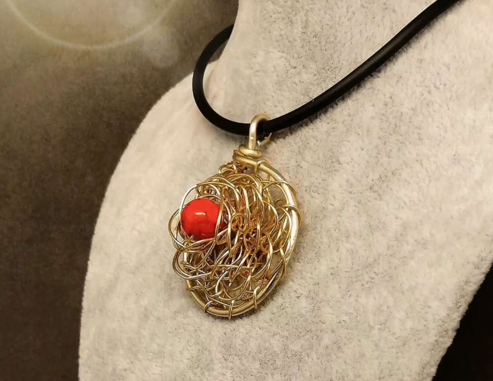 pendentif créé en fil aluminium doré en forme de fleur et pierre naturelle howlite rouge fixée au centre