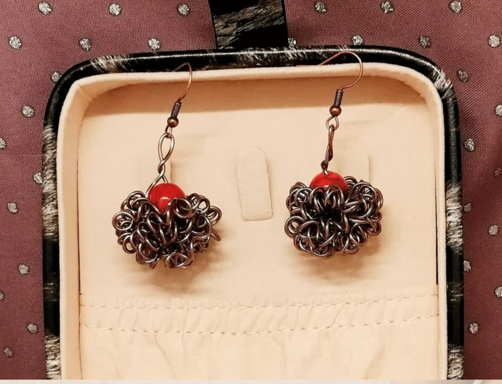 boucles d'oreilles Crazy avec pierre naturelle Howlite rouge qui est entourée de fils aluminium marron.
