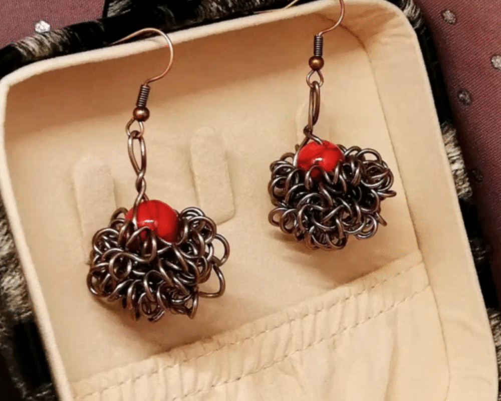 boucles d'oreilles Crazy avec pierre naturelle Howlite rouge qui est entourée de fils aluminium marron.