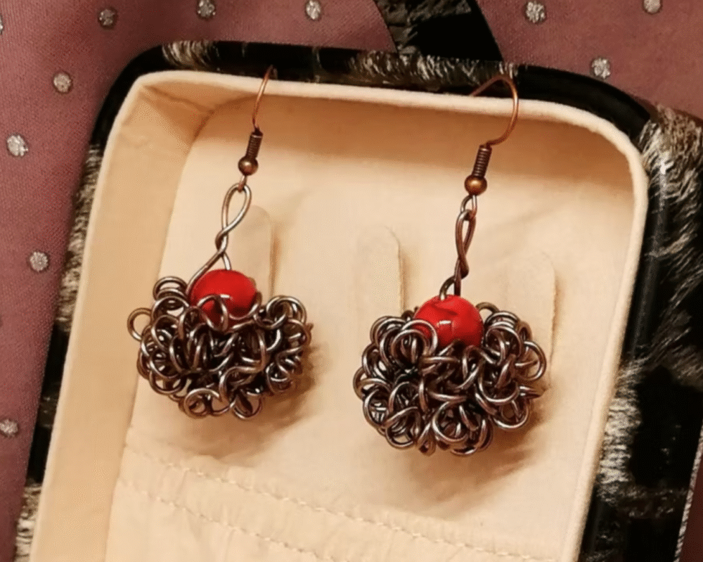 boucles d'oreilles Crazy avec pierre naturelle Howlite rouge qui est entourée de fils aluminium marron.