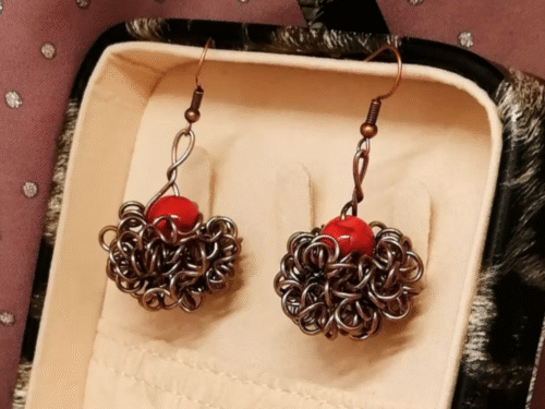 boucles d'oreilles Crazy avec pierre naturelle Howlite rouge qui est entourée de fils aluminium marron.