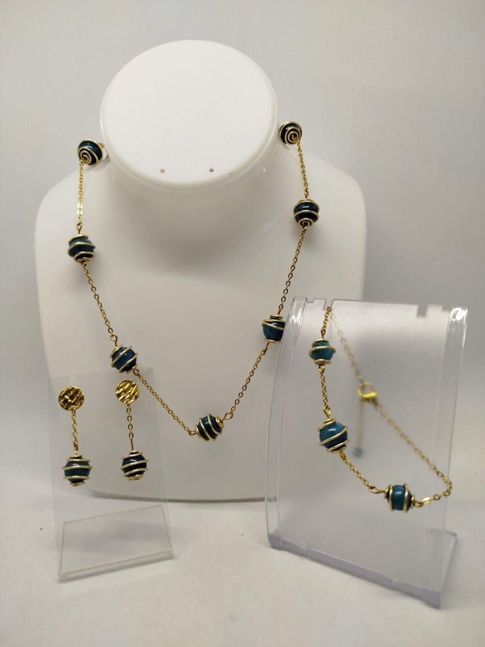 ensemble trois pièces essentielles : un collier, un bracelet, et une paire de boucles d'oreilles. Une chaîne en acier inoxydable doré.