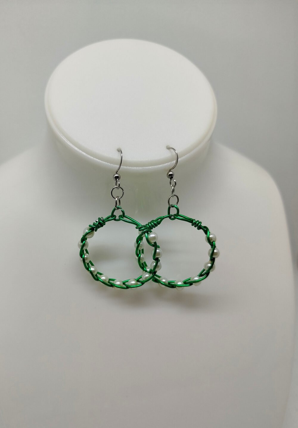 créoles tressées avec du fil aluminium vert et avec des perles couleur nacré fixées à des crochets hypoallergéniques