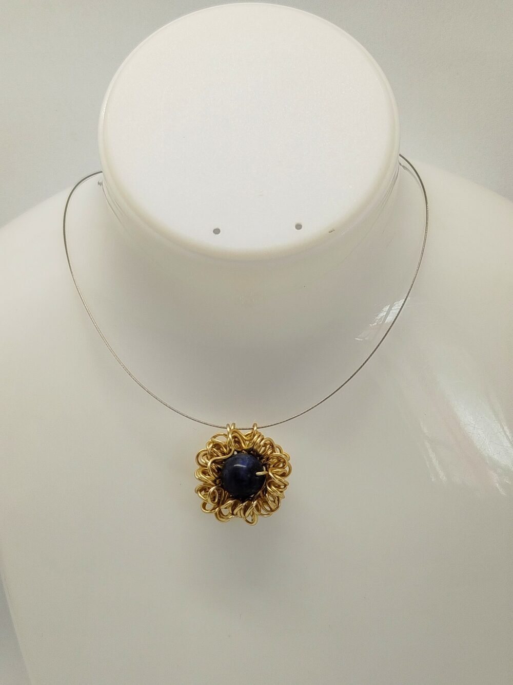 pendentif en fil d'aluminium doré qui entoure une belle pierre naturelle lapis lazuli fixé sur câble à bijoux