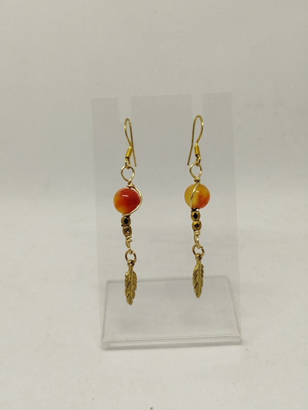 boucles d'oreilles soigneusement créé avec des pierres naturelles Jaspe Orange qui sont entourées de fil aluminium couleur doré. La chaîne est en acier inoxydable couleur doré.